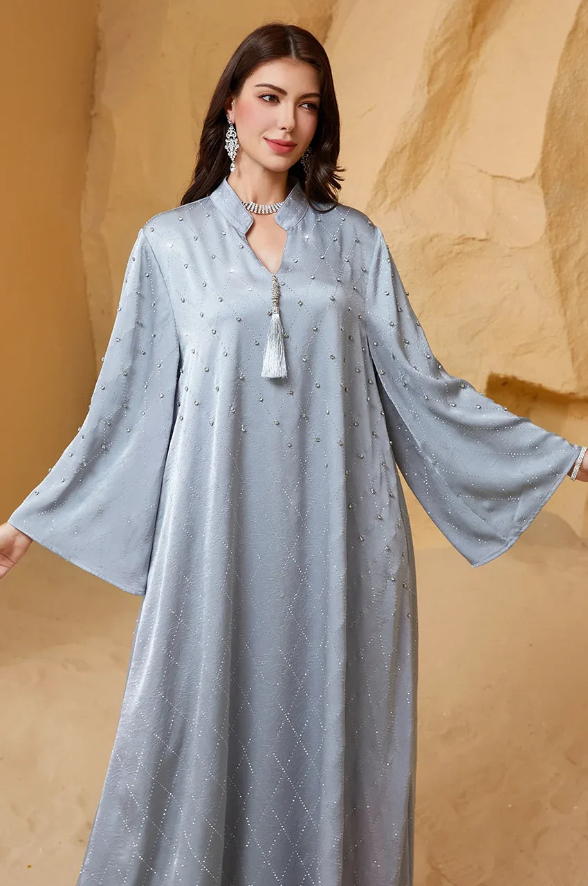 Close up of V-neck, decorative tassel, and pearl beadwork on the Elani kaftan.