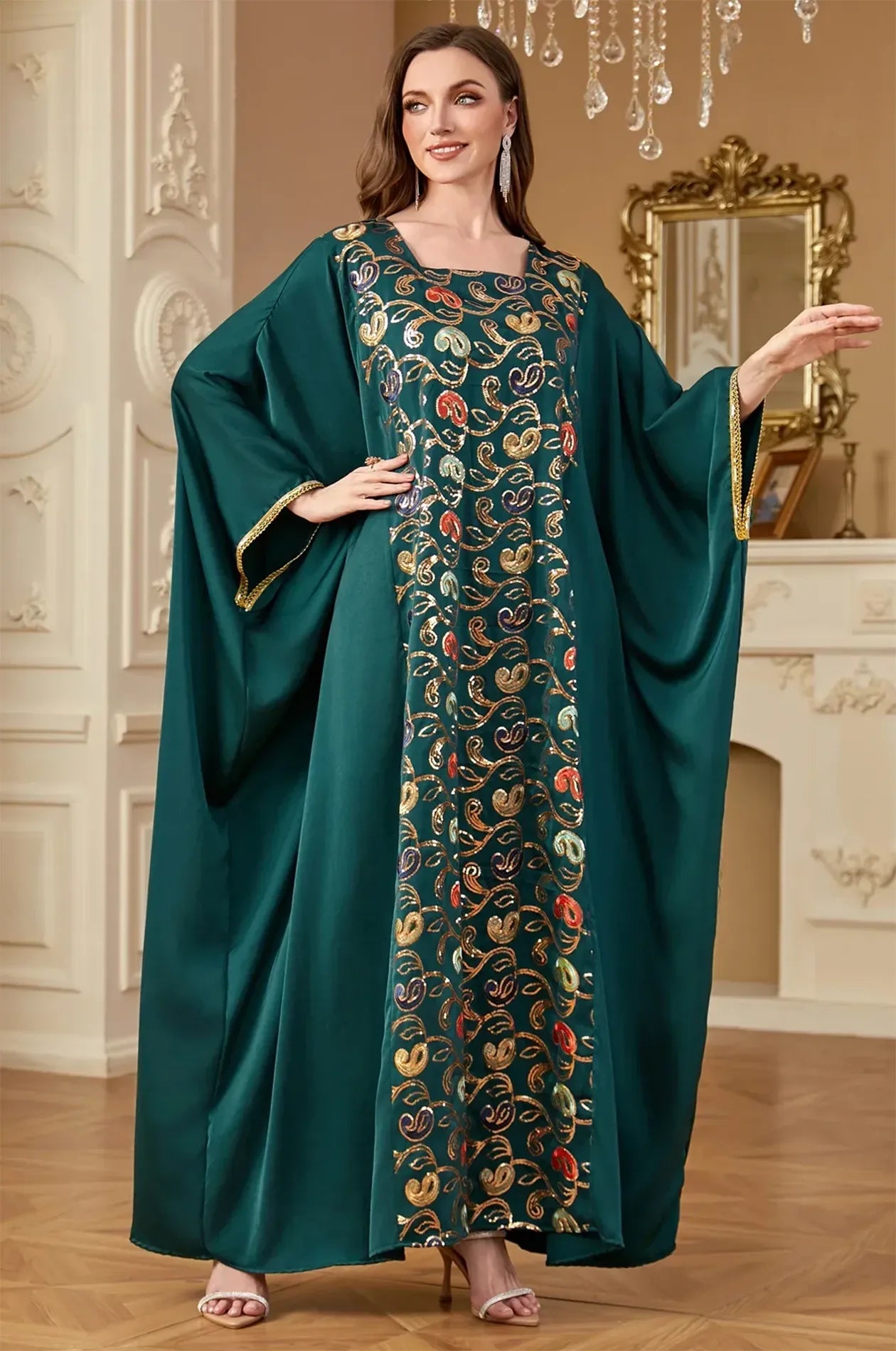 Elegant pose of the emerald green Amiri Farasha kaftan in a luxury interior setting, ideal for formal events.