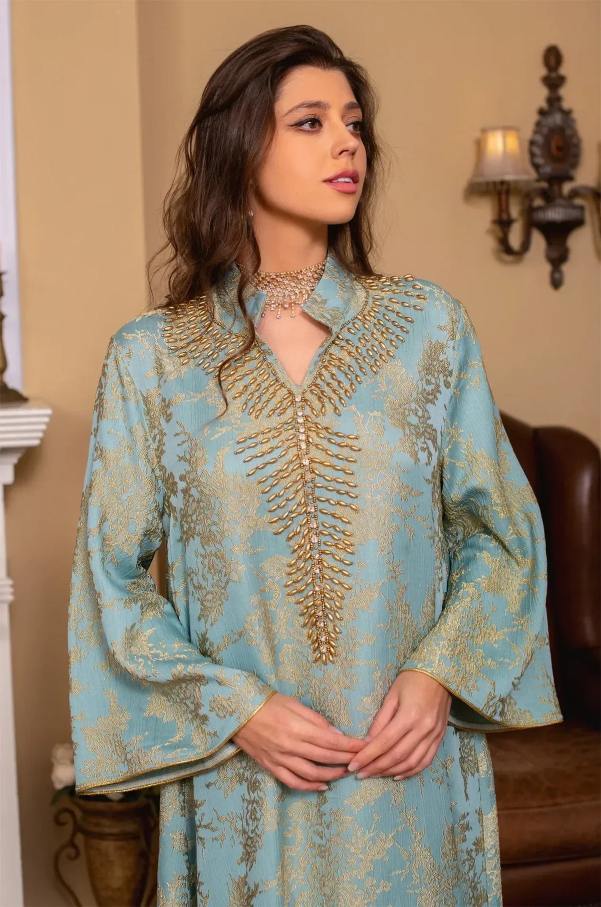 Close-up portrait of the light blue Estel kaftan highlighting the intricate gold cascading beadwork and V-neckline.