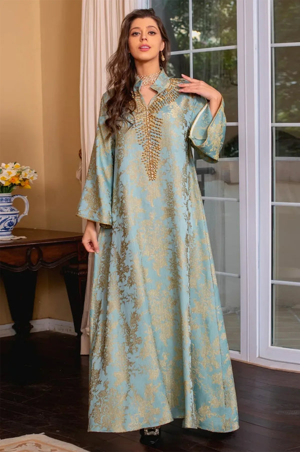 Model posing in the light blue Estel kaftan with a hand on her shoulder in front of white French doors.