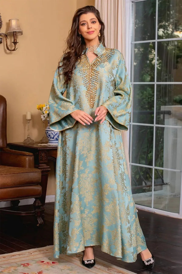 Full-body lifestyle shot of the Estel light blue kaftan standing in a luxurious room with a fireplace and vintage decor.
