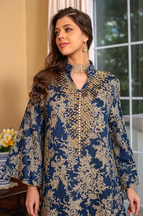Close-up portrait shot focusing on the intricate gold cascading beadwork and V-neckline of the navy blue Estel kaftan.