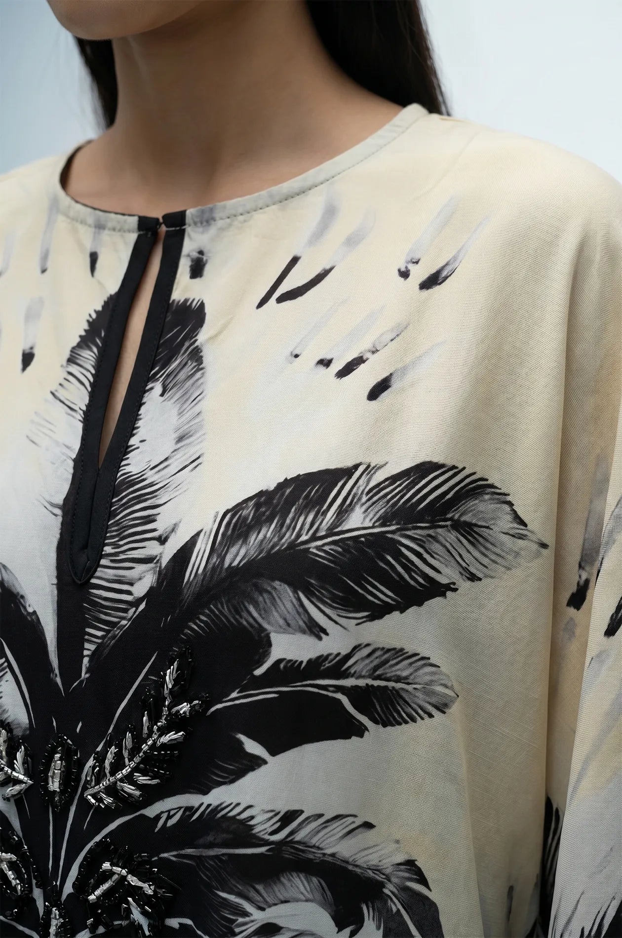 Close-up of flamingo kaftan keyhole neckline with hand-beaded palm detail