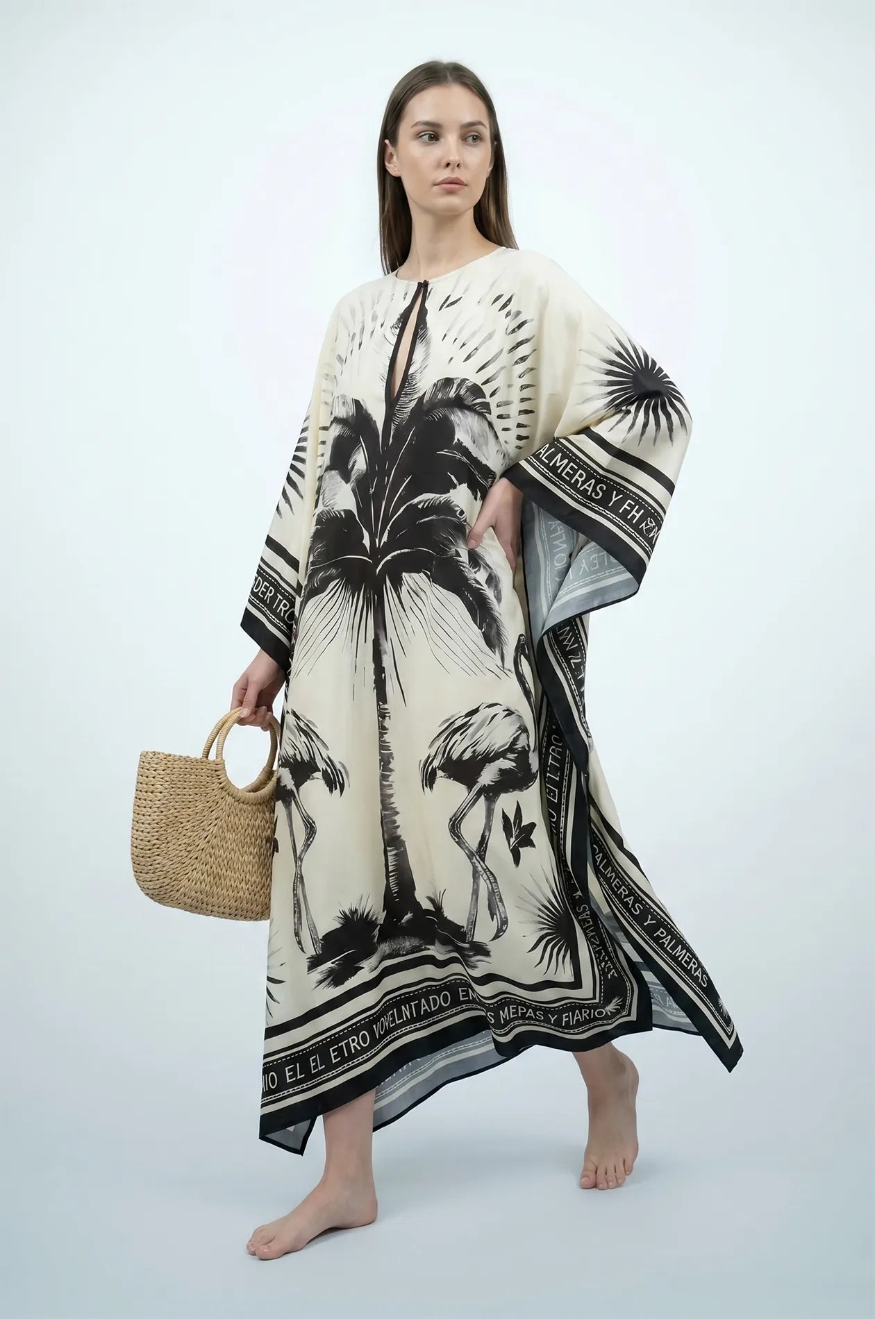 Woman holding straw bag in black and cream flamingo print kaftan