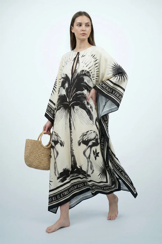 Woman holding straw bag in black and cream flamingo print kaftan