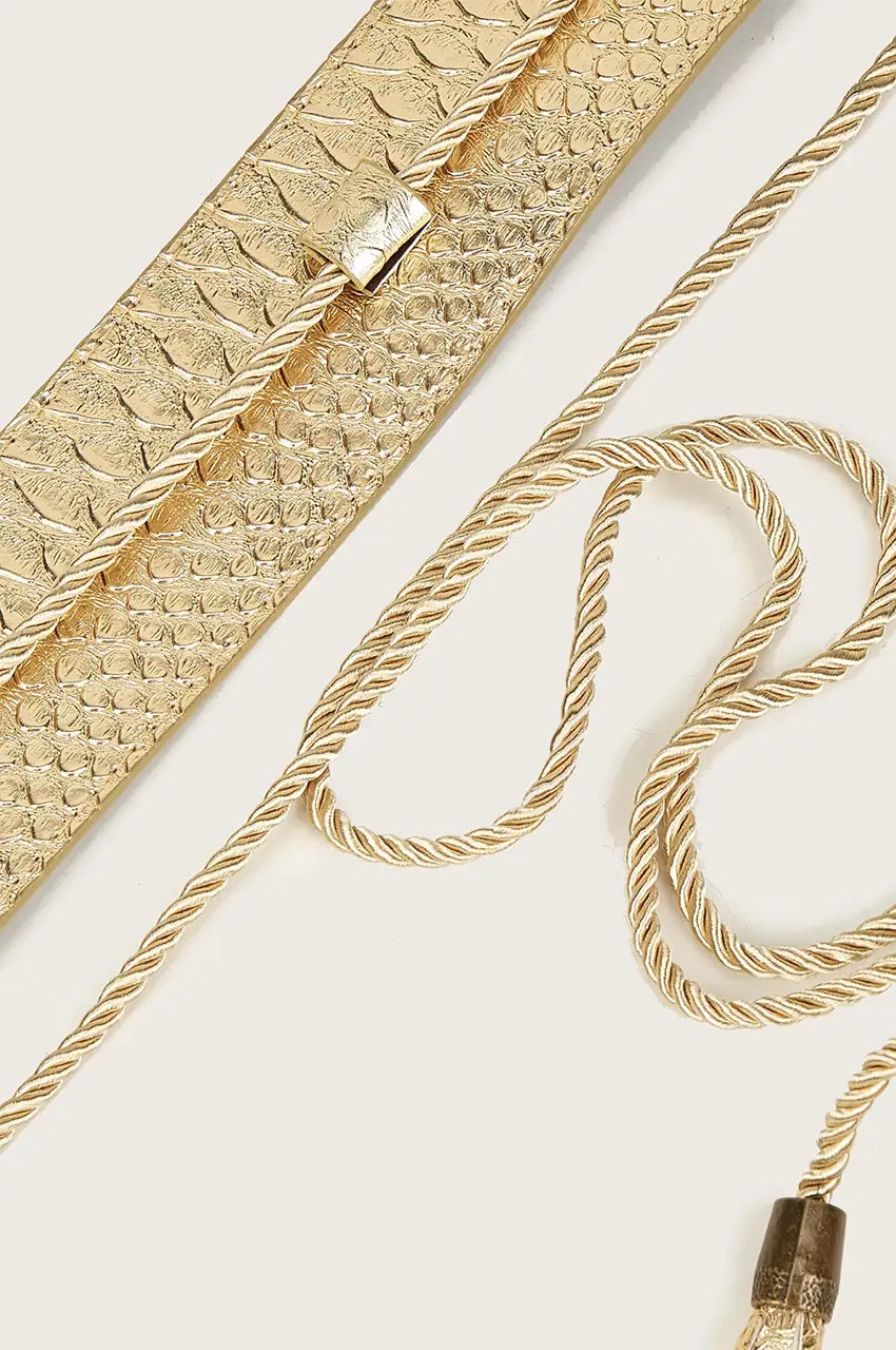 Macro detail of the twisted rope trim and loop mechanism on a gold waist belt.