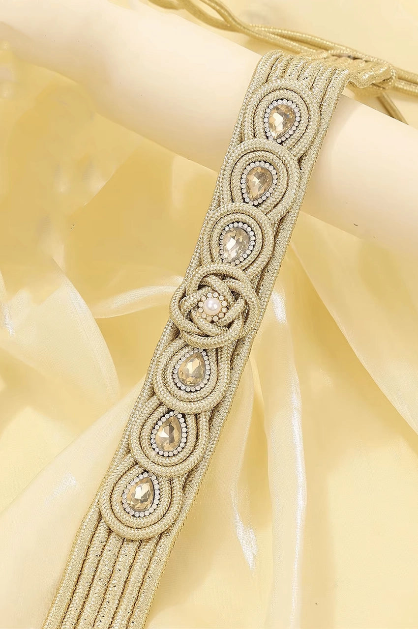 Close-up of champagne gold braided cord belt featuring teardrop rhinestones and central knot design.