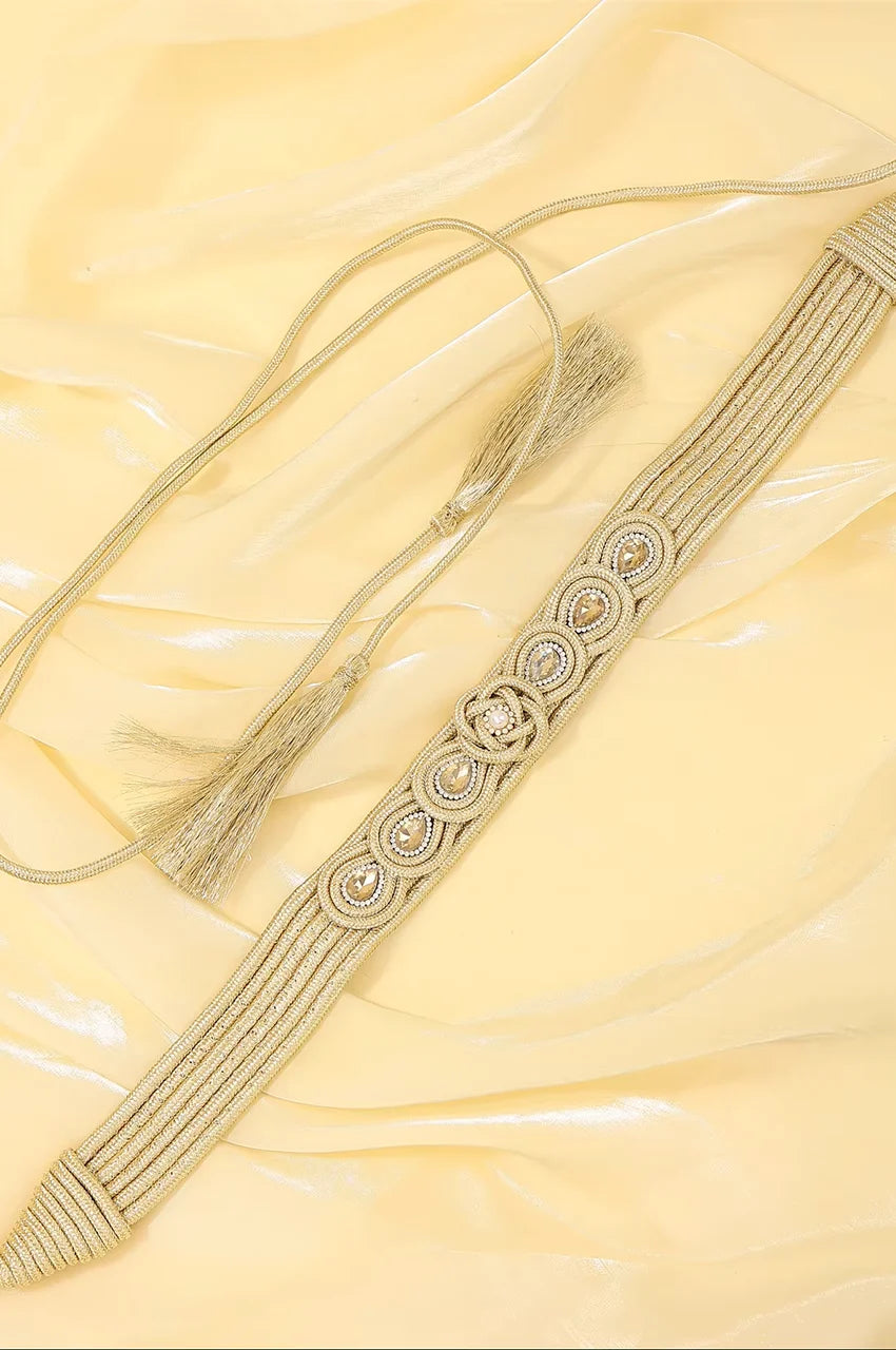 Flat lay display of champagne gold cord belt with adjustable tassel ties on a light background.