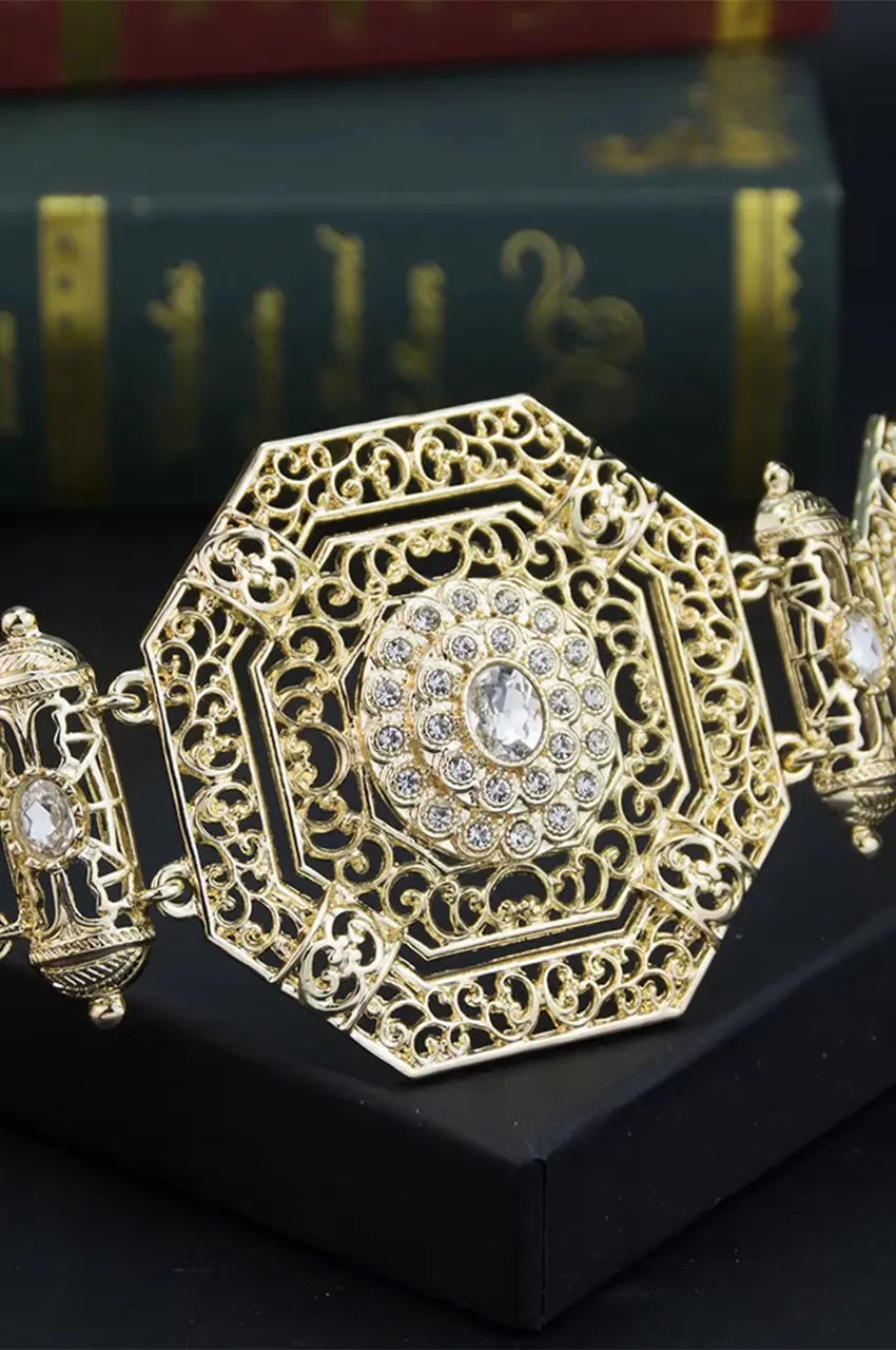Macro close-up of the gold octagonal metal plate featuring intricate filigree work and a central crystal.