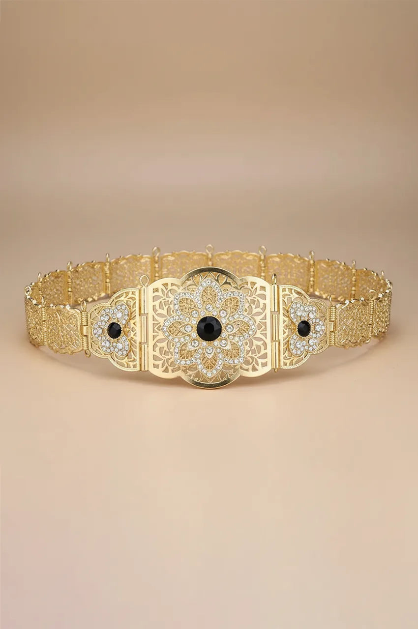 Full view of gold floral filigree belt featuring a black crystal centerpiece.