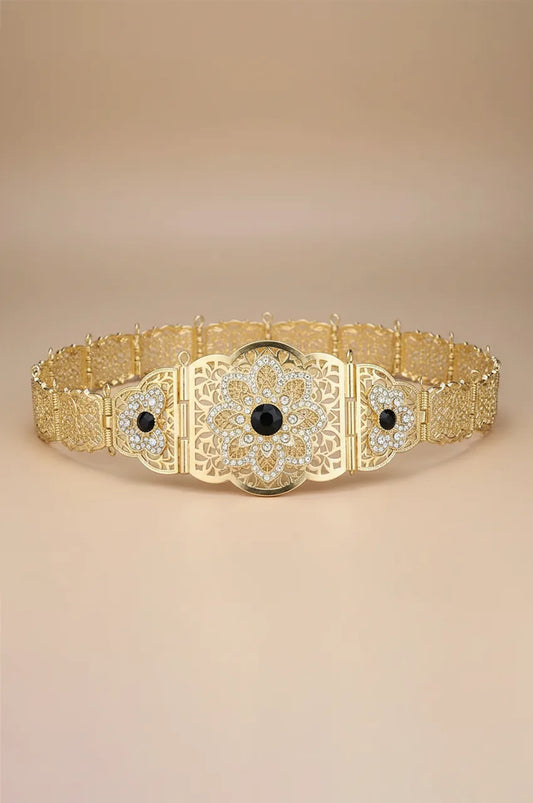 Full view of gold floral filigree belt featuring a black crystal centerpiece.