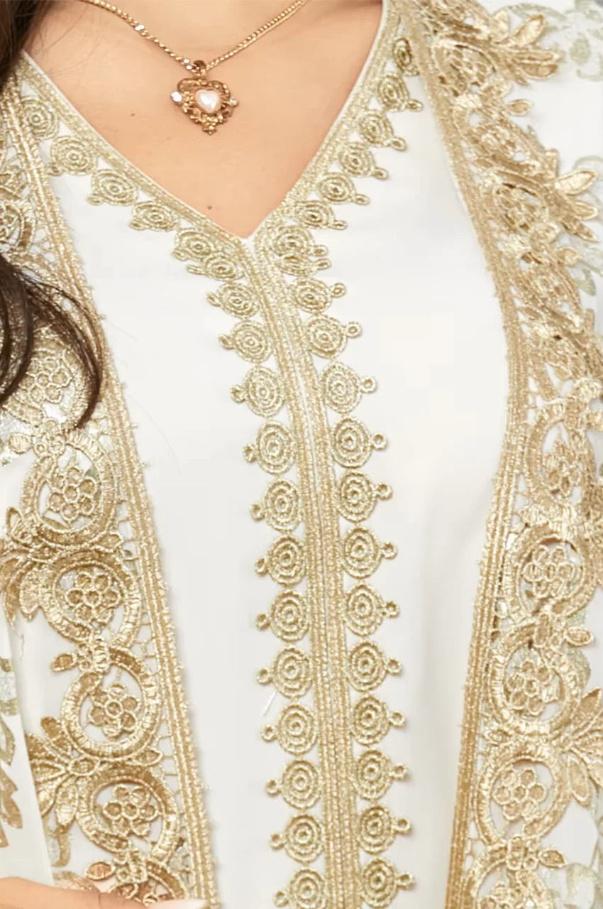 Close-up of gold floral embroidery and Sfifa needlework on white kaftan dress.