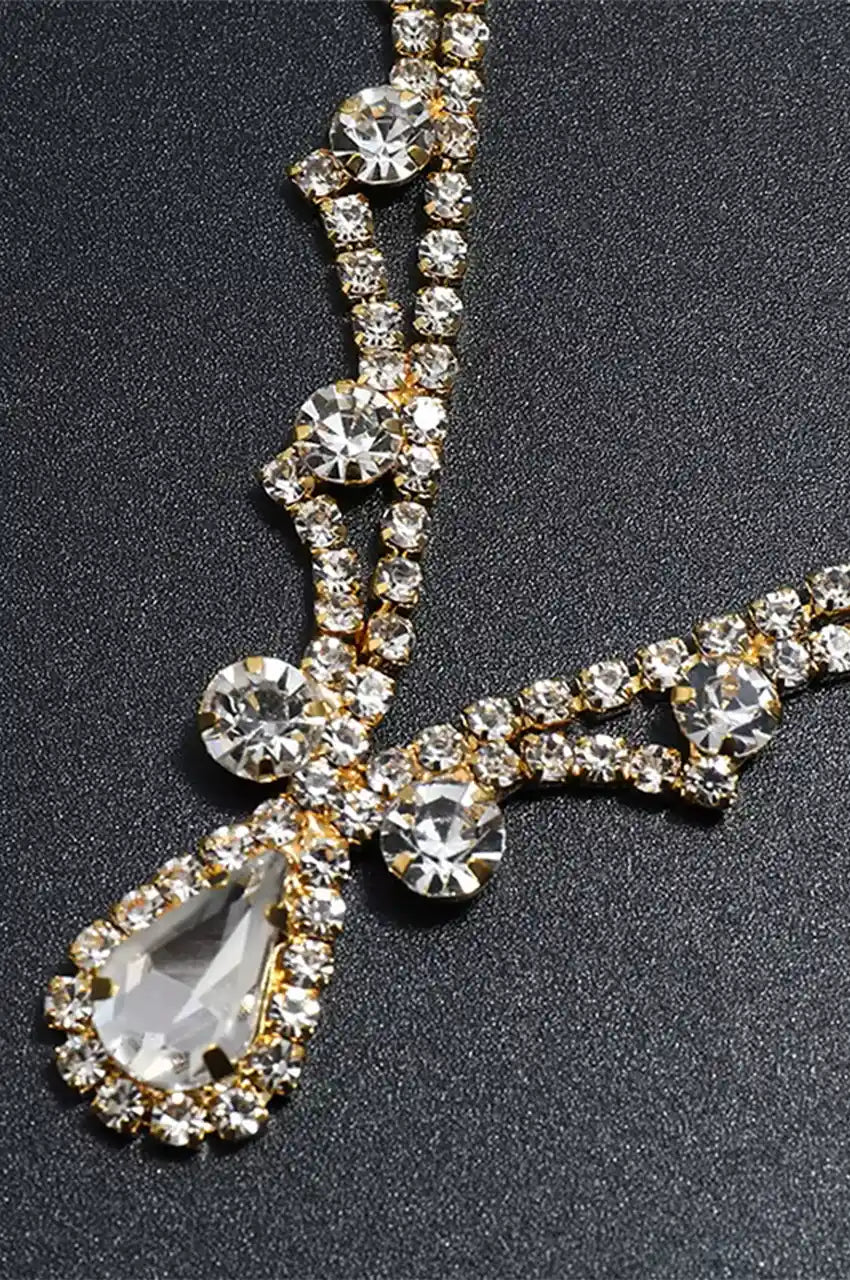 Close-up detail of the gold headpiece showing the teardrop crystal and rhinestone chain.