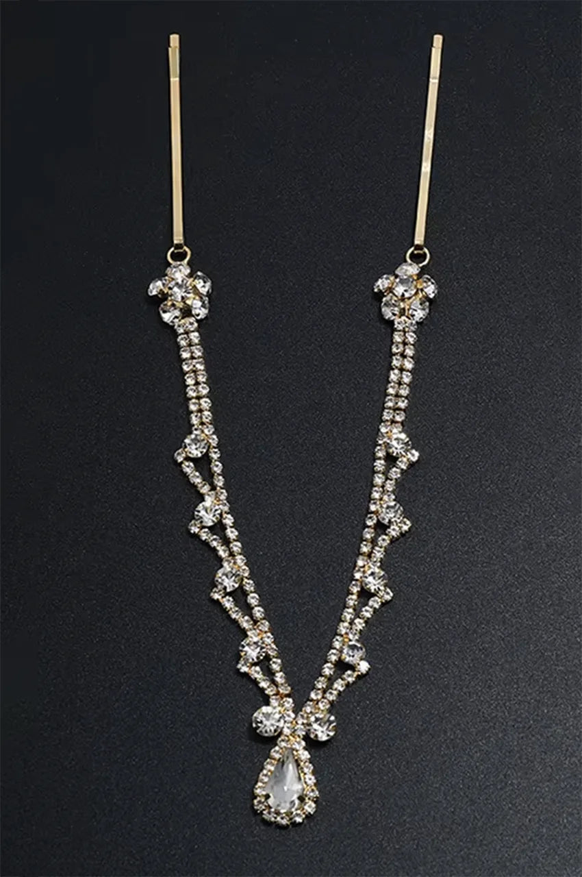 Gold rhinestone headpiece displayed on a black background, emphasizing the V-shape and crystal detail.