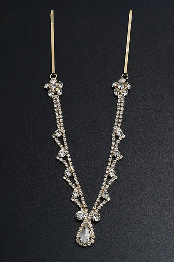 Gold rhinestone headpiece displayed on a black background, emphasizing the V-shape and crystal detail.