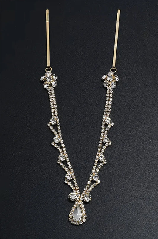 Gold rhinestone headpiece displayed on a black background, emphasizing the V-shape and crystal detail.