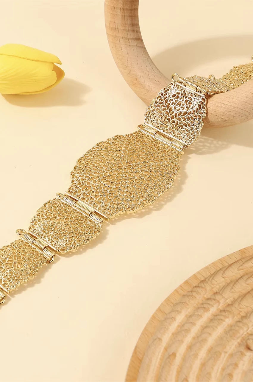 Close-up of the hollow-out floral pattern and hinges on the gold waist belt.