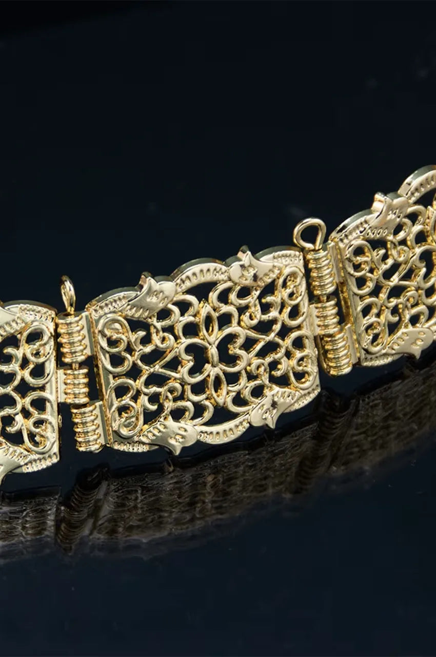 Macro shot of the intricate floral openwork design on the gold square metal belt plates.