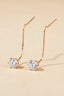 Minimalist gold chain pull-through earrings displayed on a beige background.
