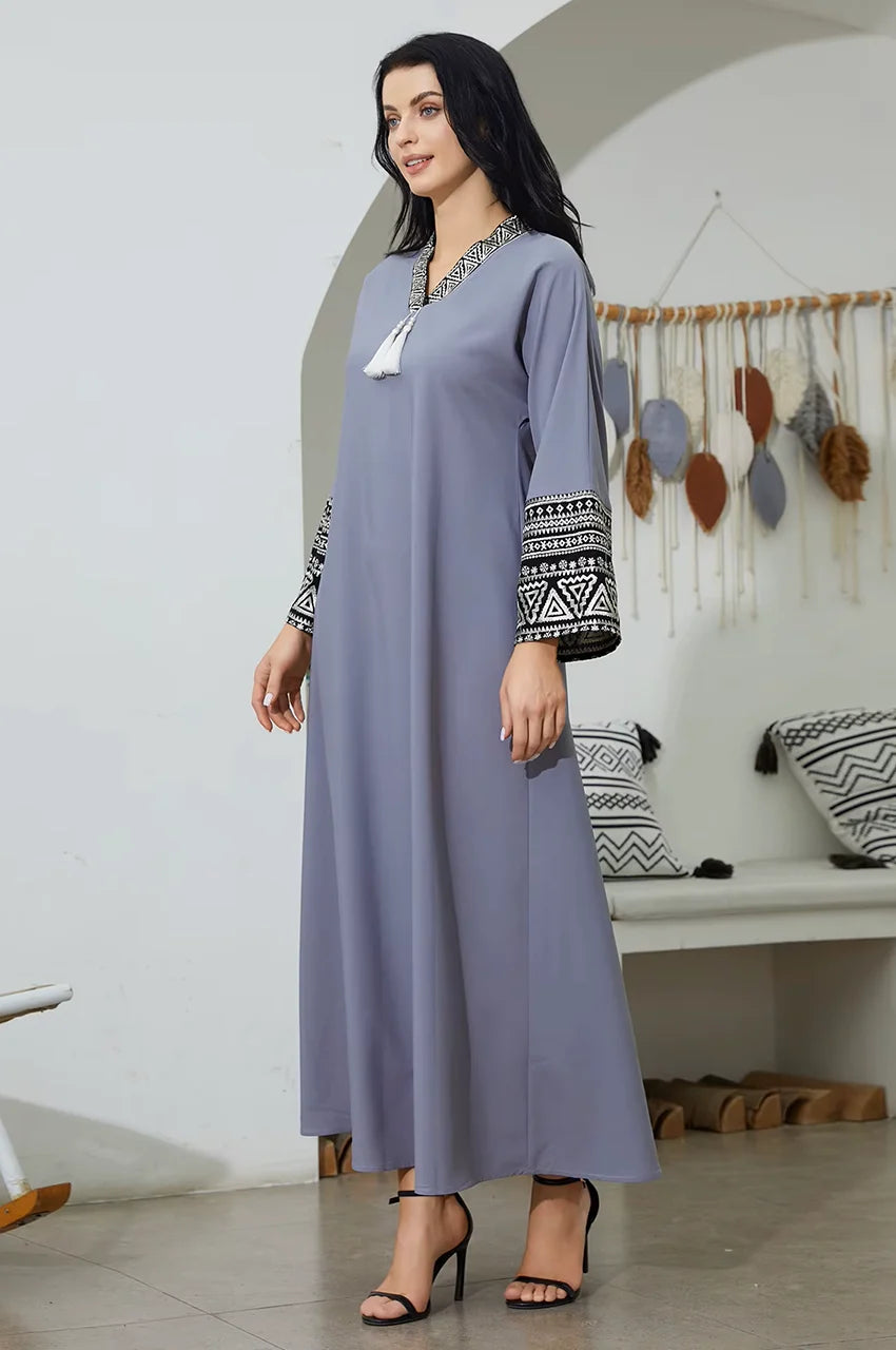 Model wearing modest gray kaftan dress with white tassels.