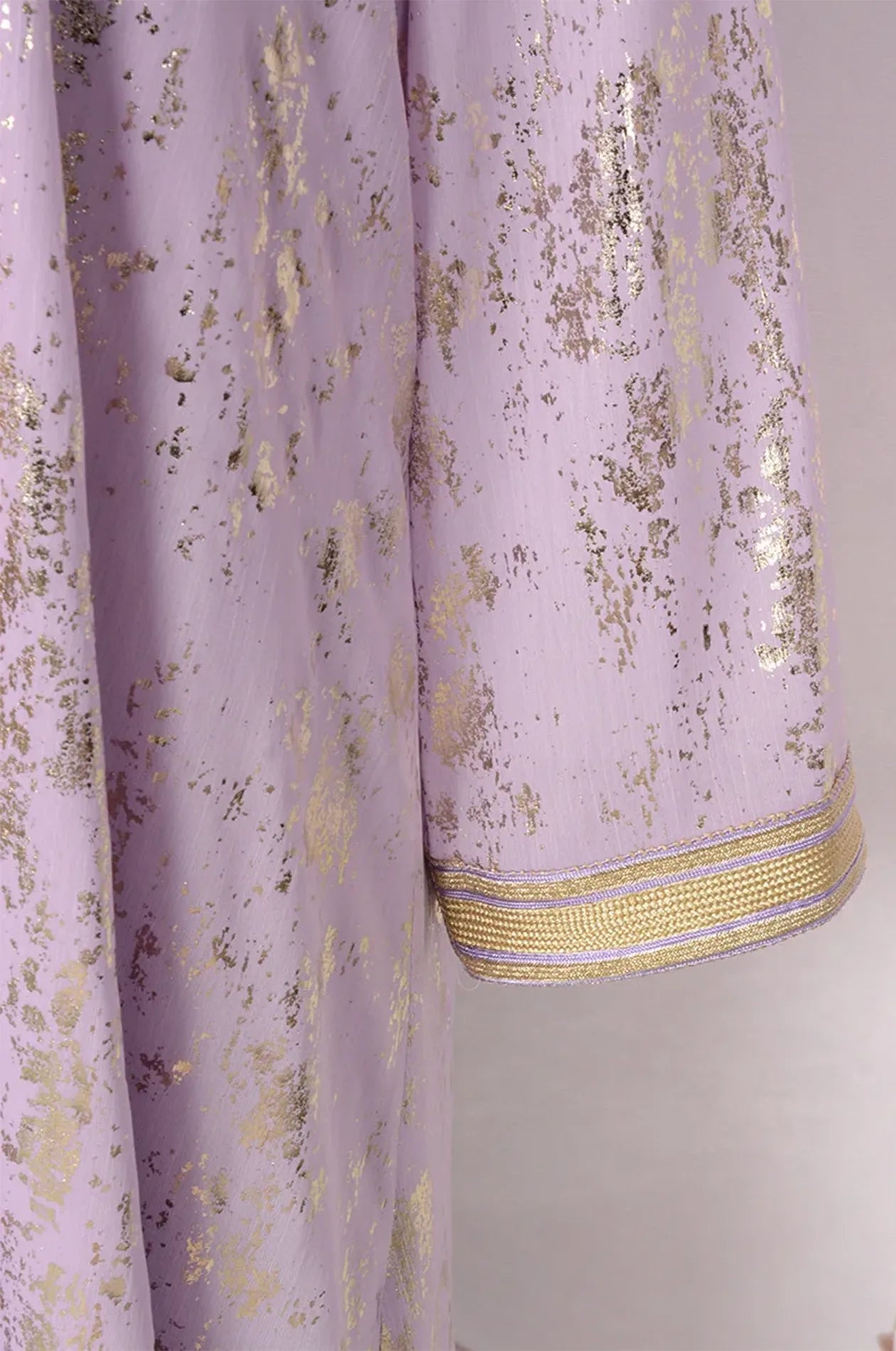 Detailed texture shot of the metallic gold foil pattern on lilac fabric.
