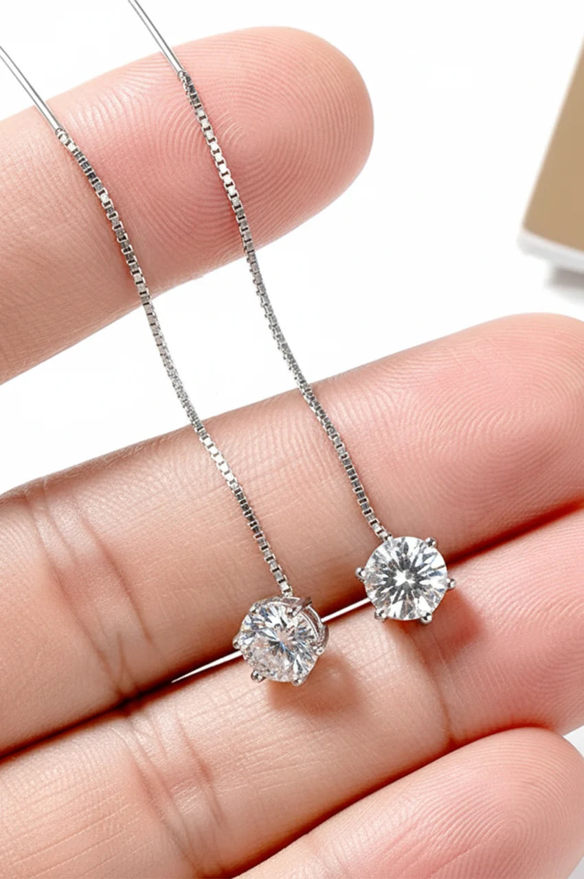 Close up of hand holding long silver moissanite threader earrings showing sparkle and chain flexibility.
