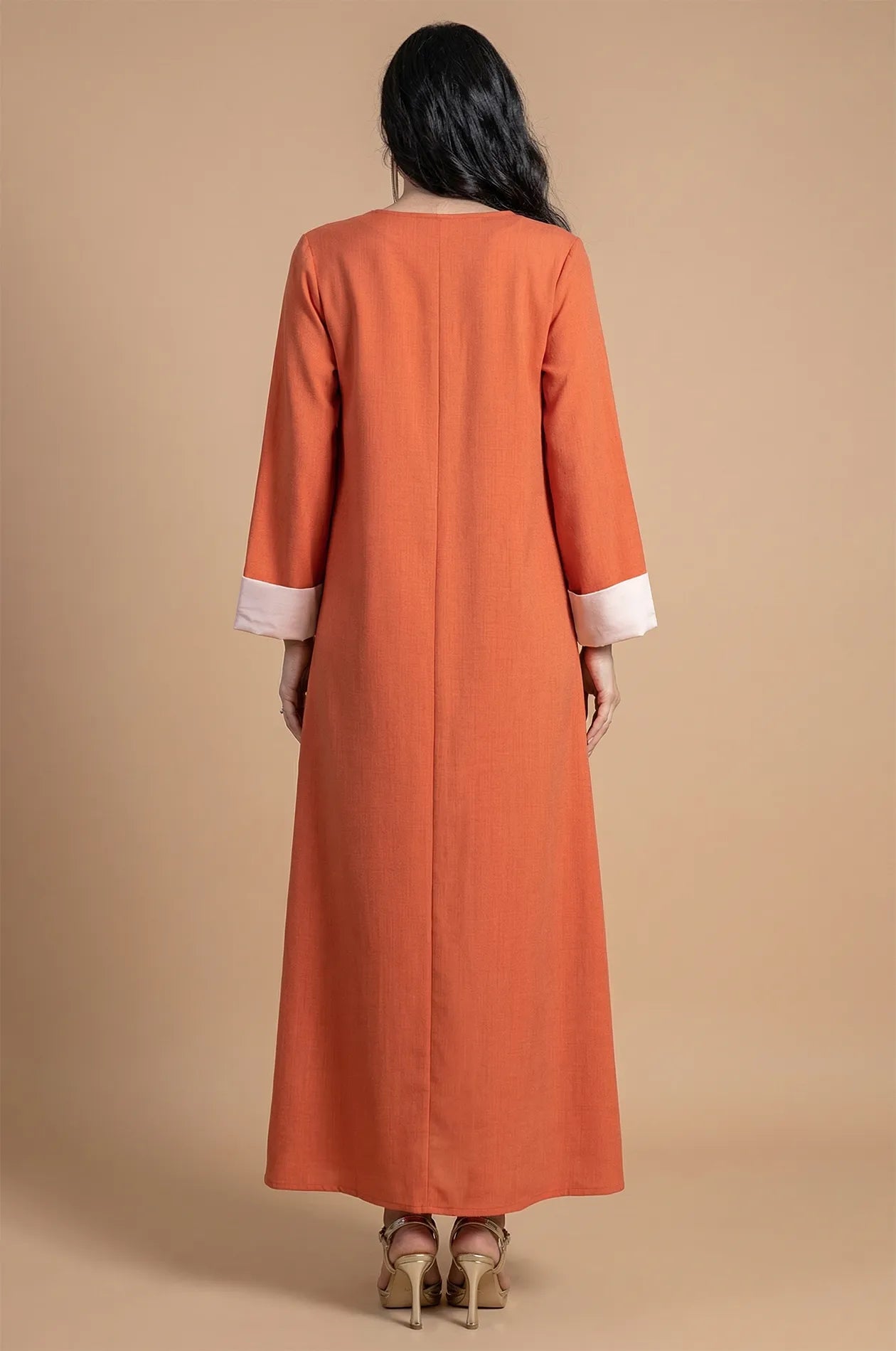 Back view of the floor-length orange Ilena kaftan showing the clean silhouette.