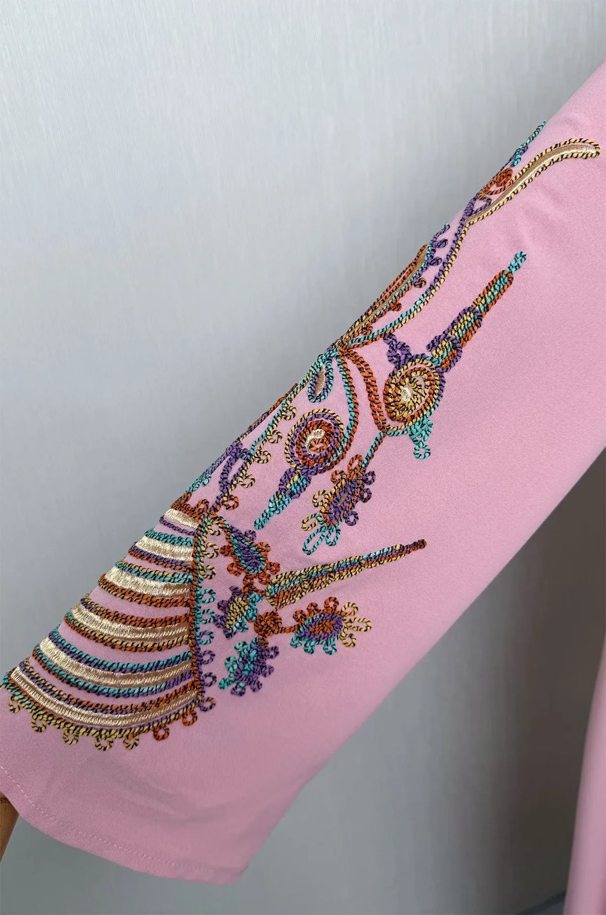 Close-up zoom of the multi-colored braided needlework on the bell sleeve of the dusty pink Inez Kaftan.