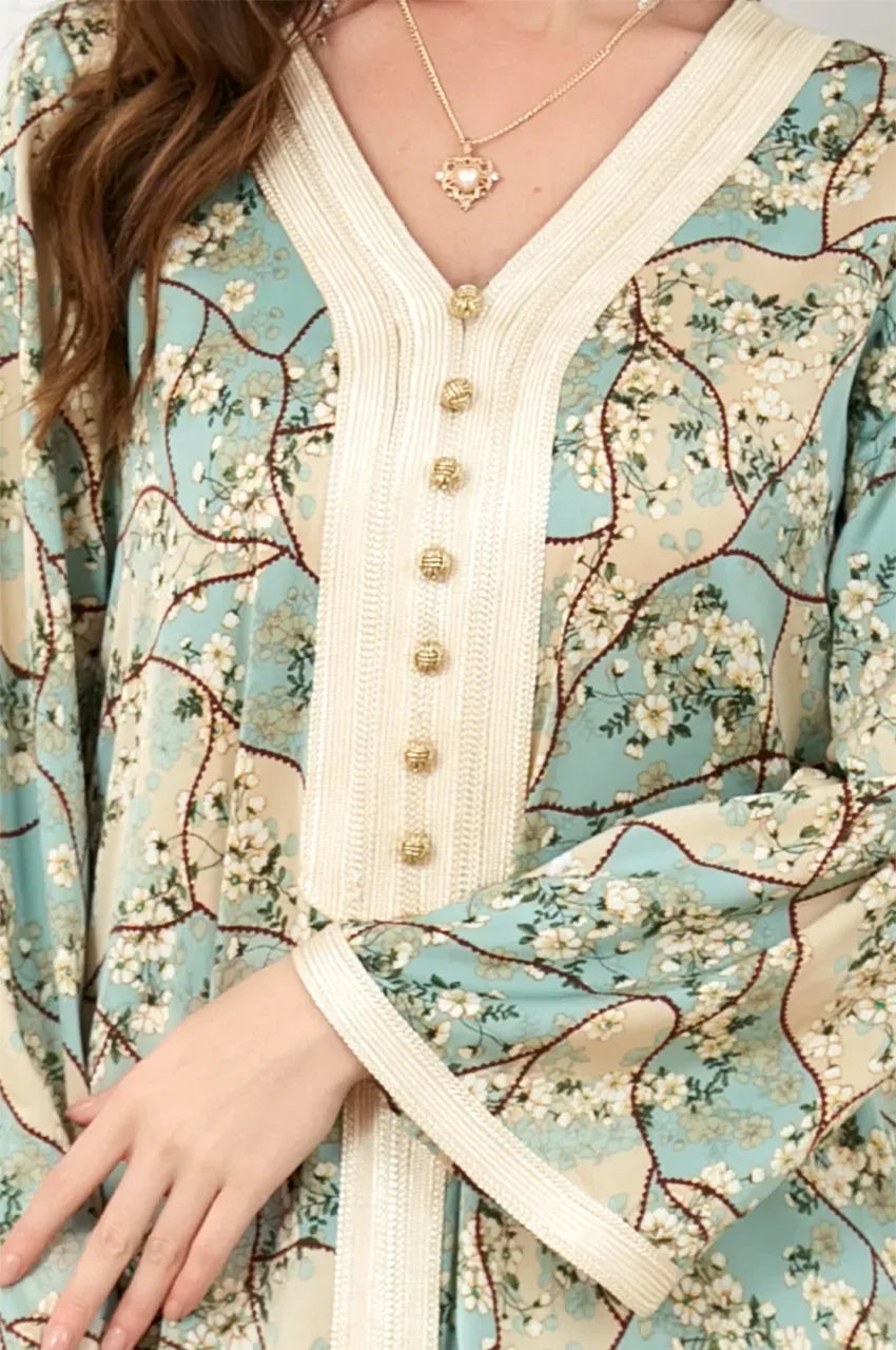Close-up of the V-neckline on the Isara green kaftan featuring ivory Sfifa embroidery and traditional gold Aakad buttons.