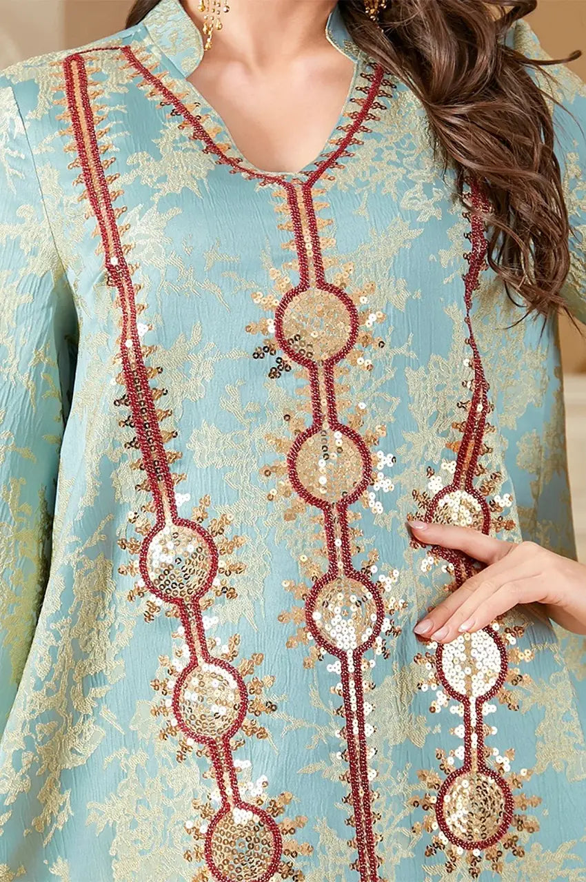 Close-up macro shot of the V-neckline, Sfifa trim, and sequin medallions on the mint kaftan.