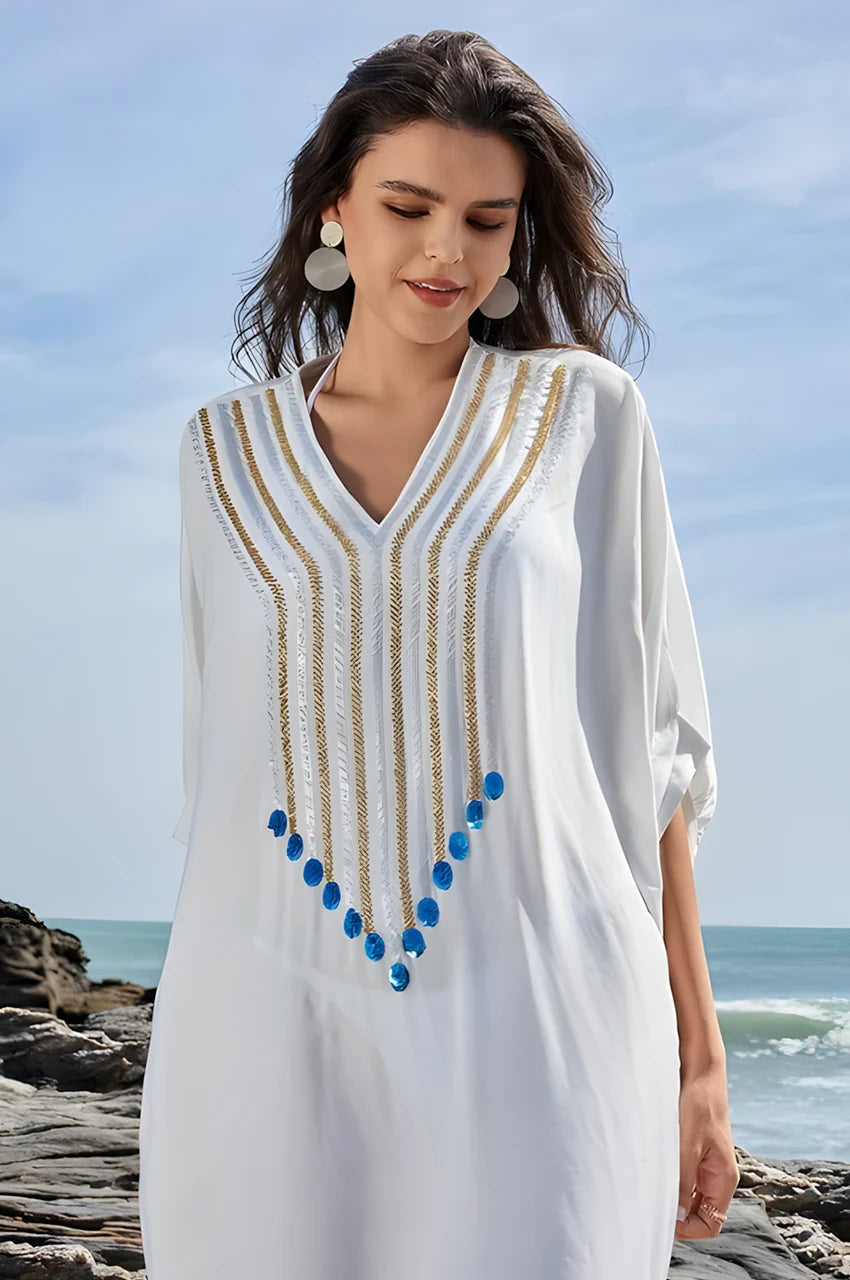 Kalila white Greek kaftan worn on coastal rocks with ocean in background