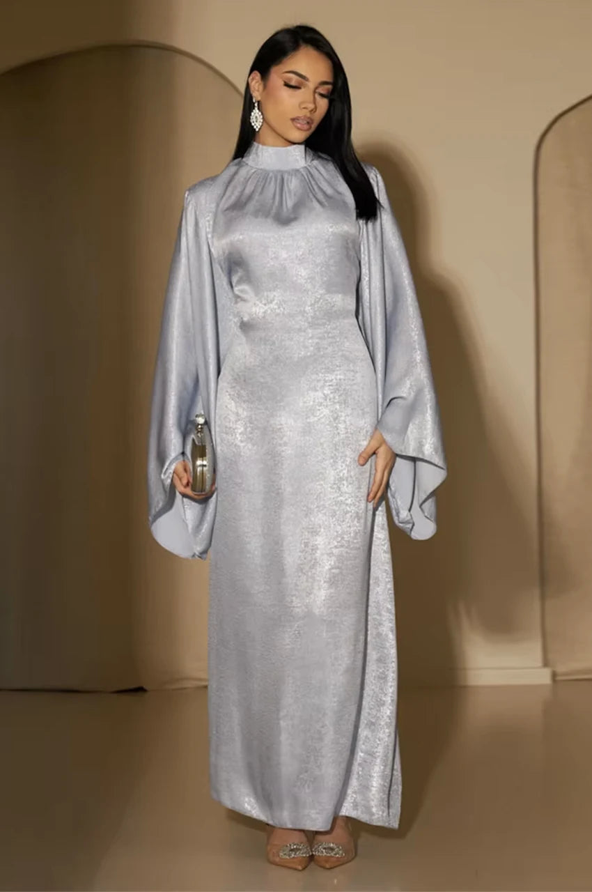 Kehlia metallic silver kaftan in soft indoor lighting, high neck and long draped sleeves