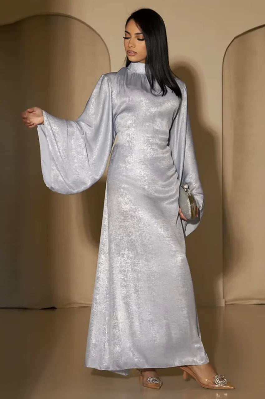 Side pose of Kehlia metallic silver kaftan showing fluid draped sleeves and shimmering fabric