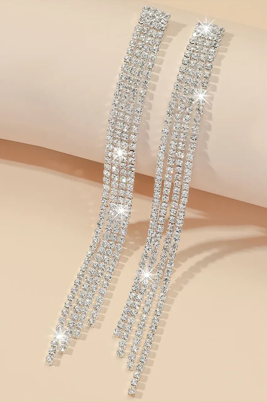 Angled flat lay of four-strand rhinestone tassel earrings showing flexibility and shine.