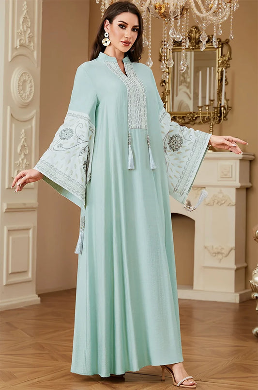 Elegant standing pose of the Cyan Nairi cotton kaftan maxi featuring decorative tassels and geometric white embroidery.