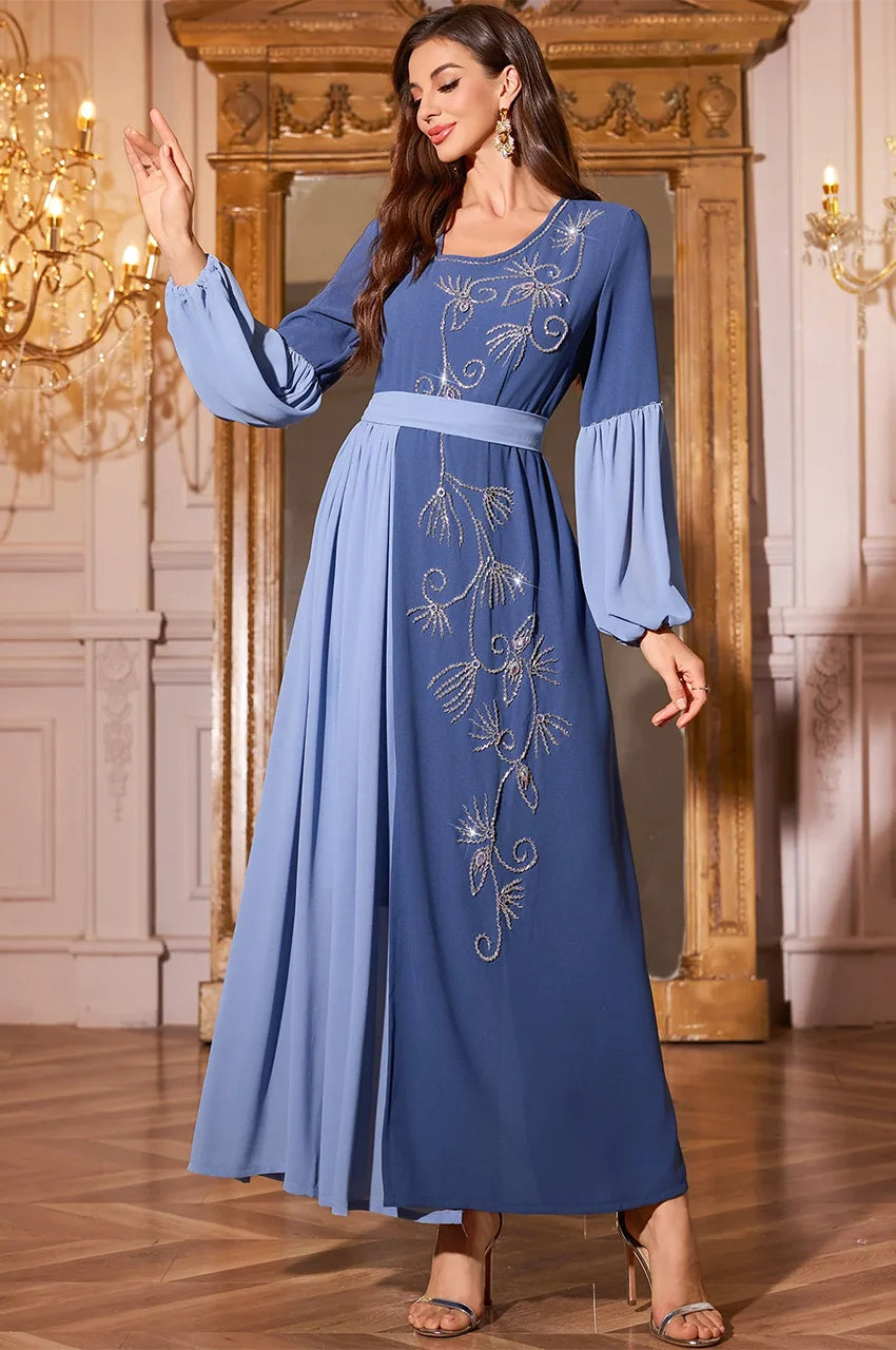 Woman wearing flowing Zaria blue pleated kaftan dress for wedding guest attire.