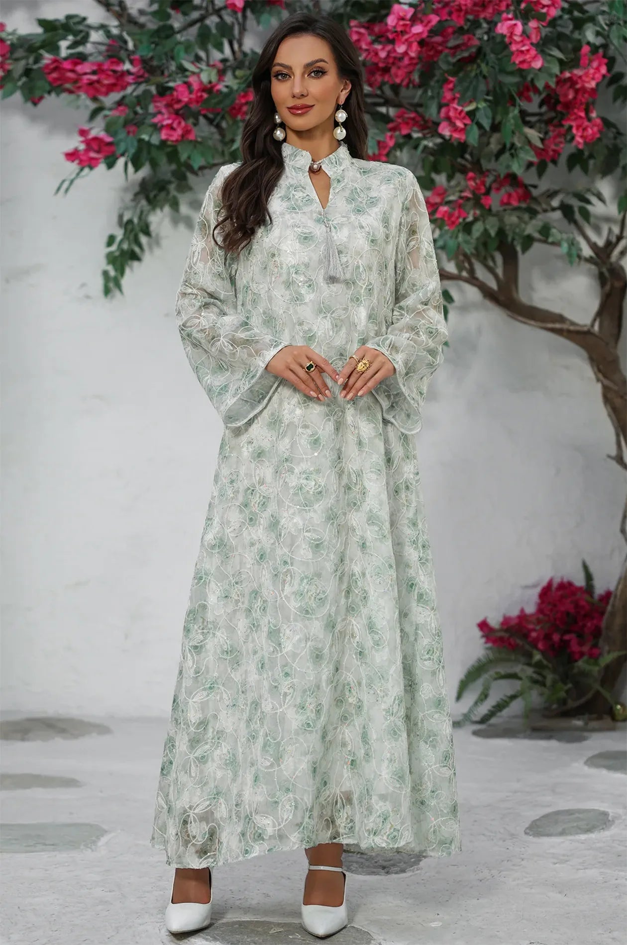 Frontal pose of the Lyana light green kaftan in a Mediterranean garden setting.