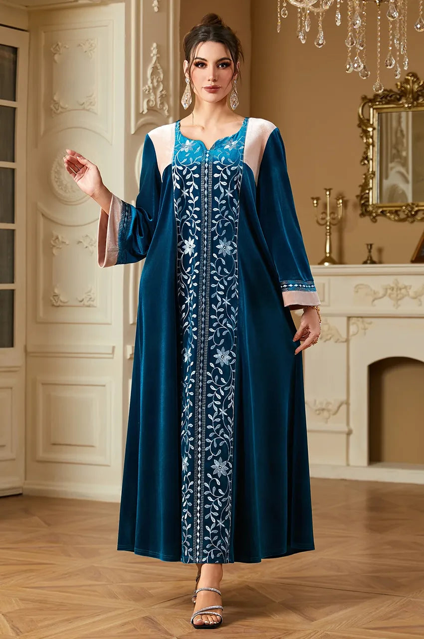 Model walking in Lylah blue velvet kaftan showing fabric movement.