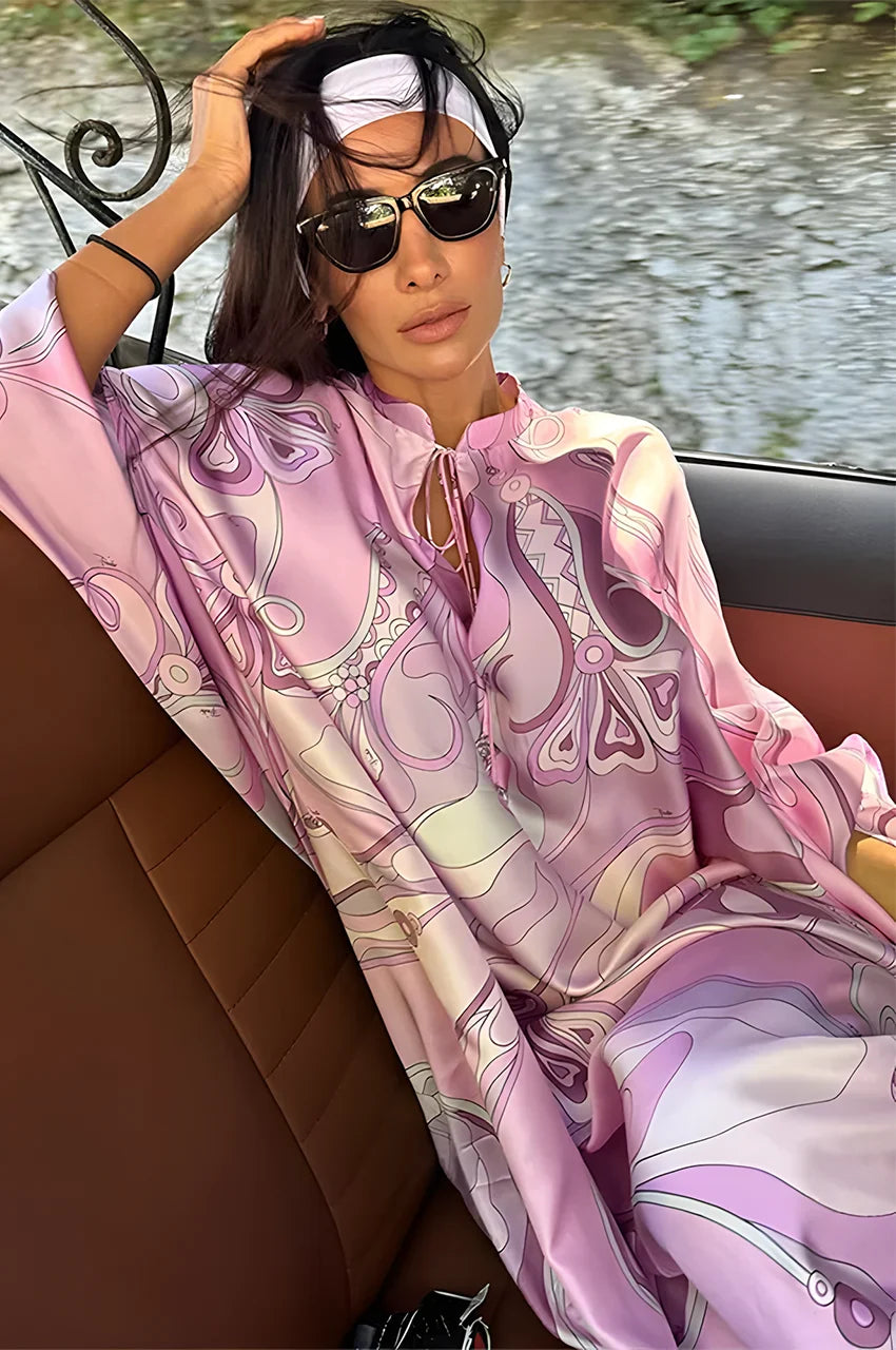 Model seated wearing Lyra Pink Floral Kaftan Dress, showing fabric flow