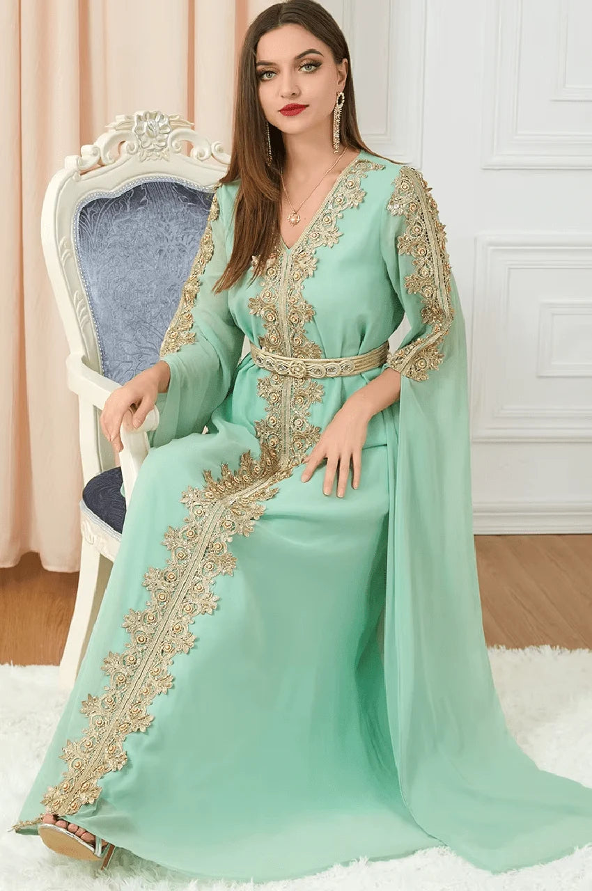 Seated model wearing Maelis green Moroccan traditional kaftan with ornate embroidery