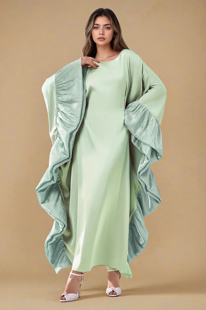 Fashion pose wearing the Malya green ruffle kaftan with fluid satin drape and sculptural ruffles