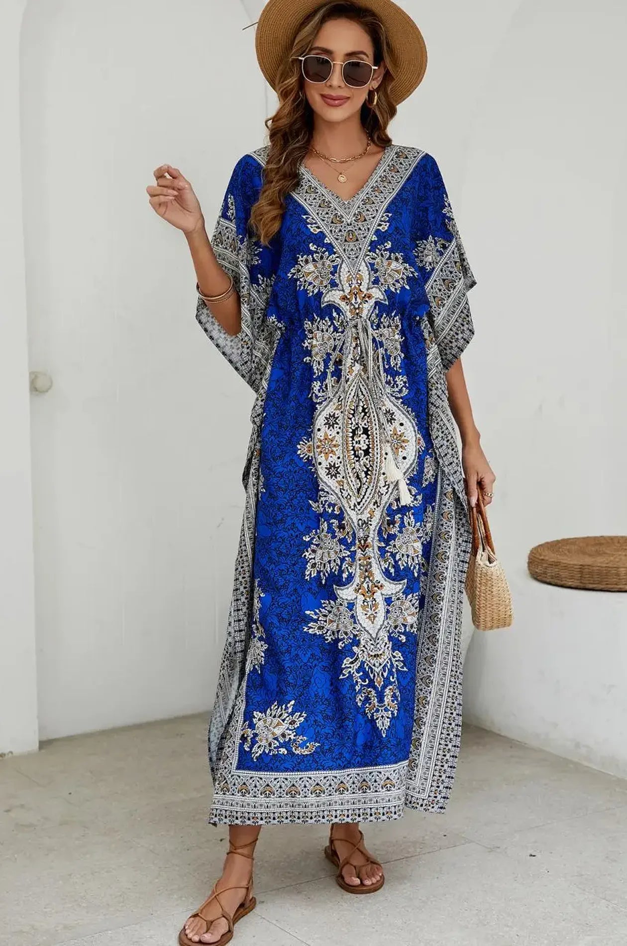 Woman in blue mandala kaftan with straw hat sunglasses and rattan bag