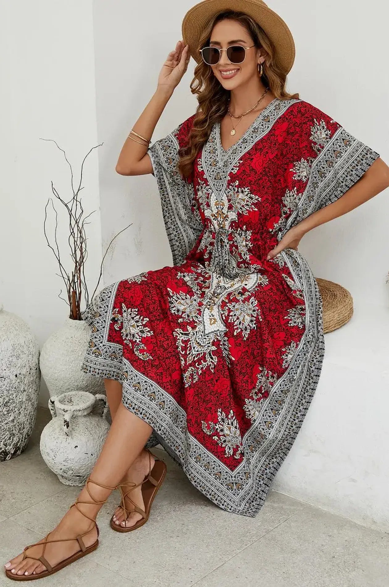 Woman seated in crimson mandala print maxi kaftan at resort