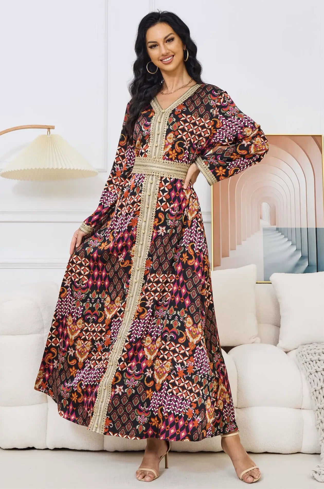 Model sitting on a white sofa wearing the Maris multicolor tribal kaftan.