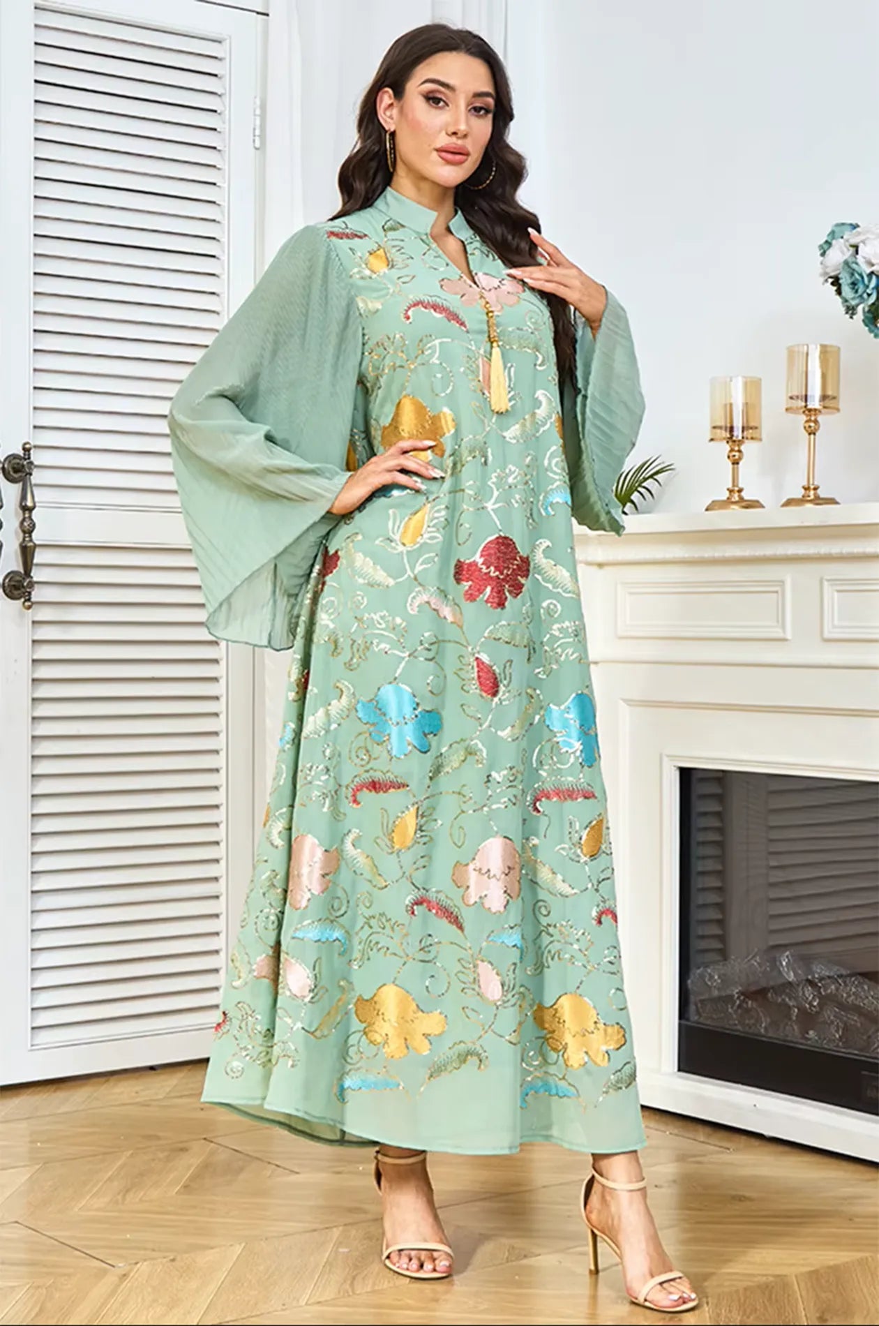 Fashion model posing in the Marylin Green Floral Sequin Kaftan, highlighting the V-neck collar and fluid pleated sleeves.