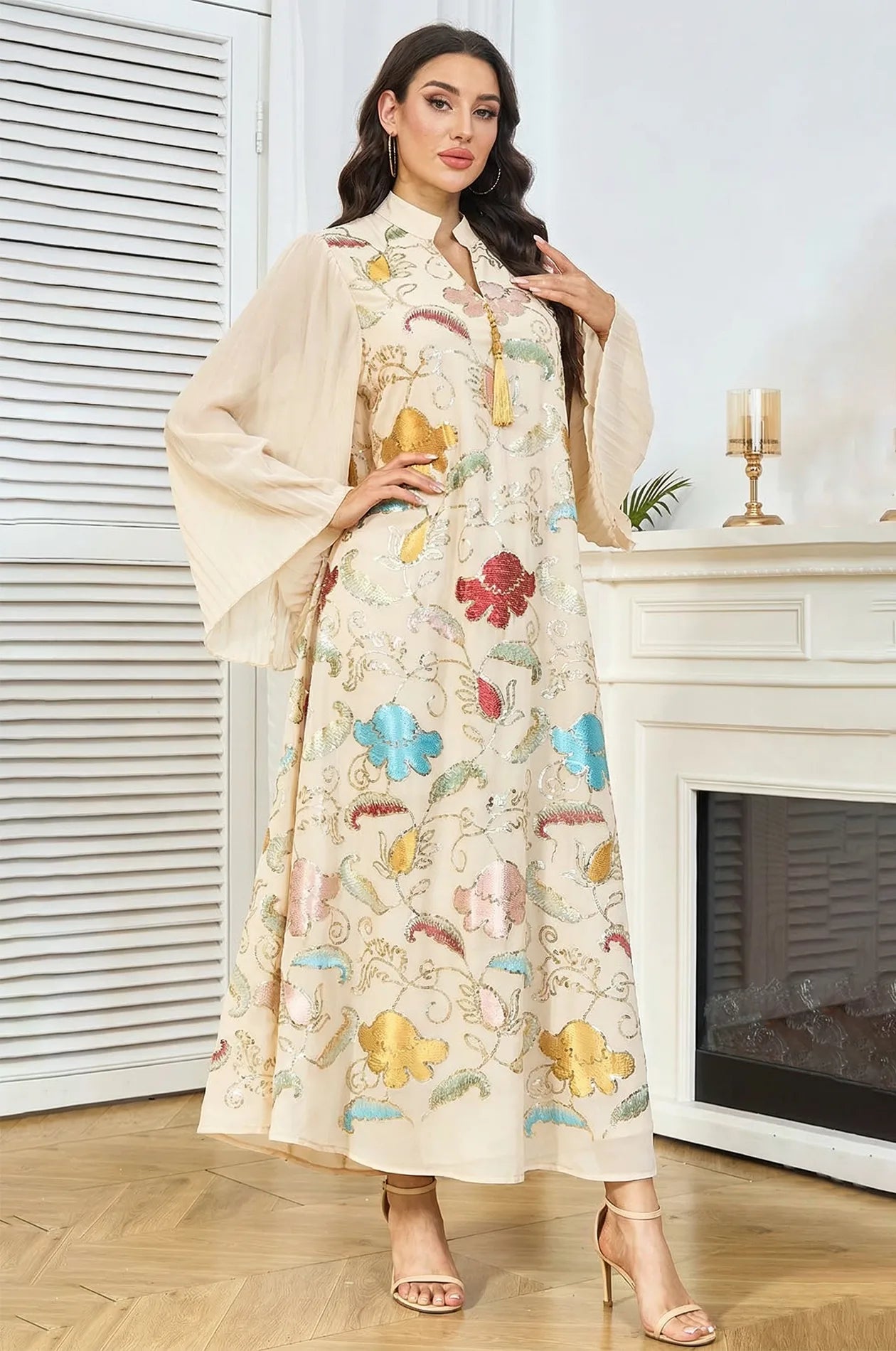 Fashion pose of the Marylin Ivory Beige Kaftan with hand on hip, highlighting the vibrant floral sequins and pleated butterfly sleeves.