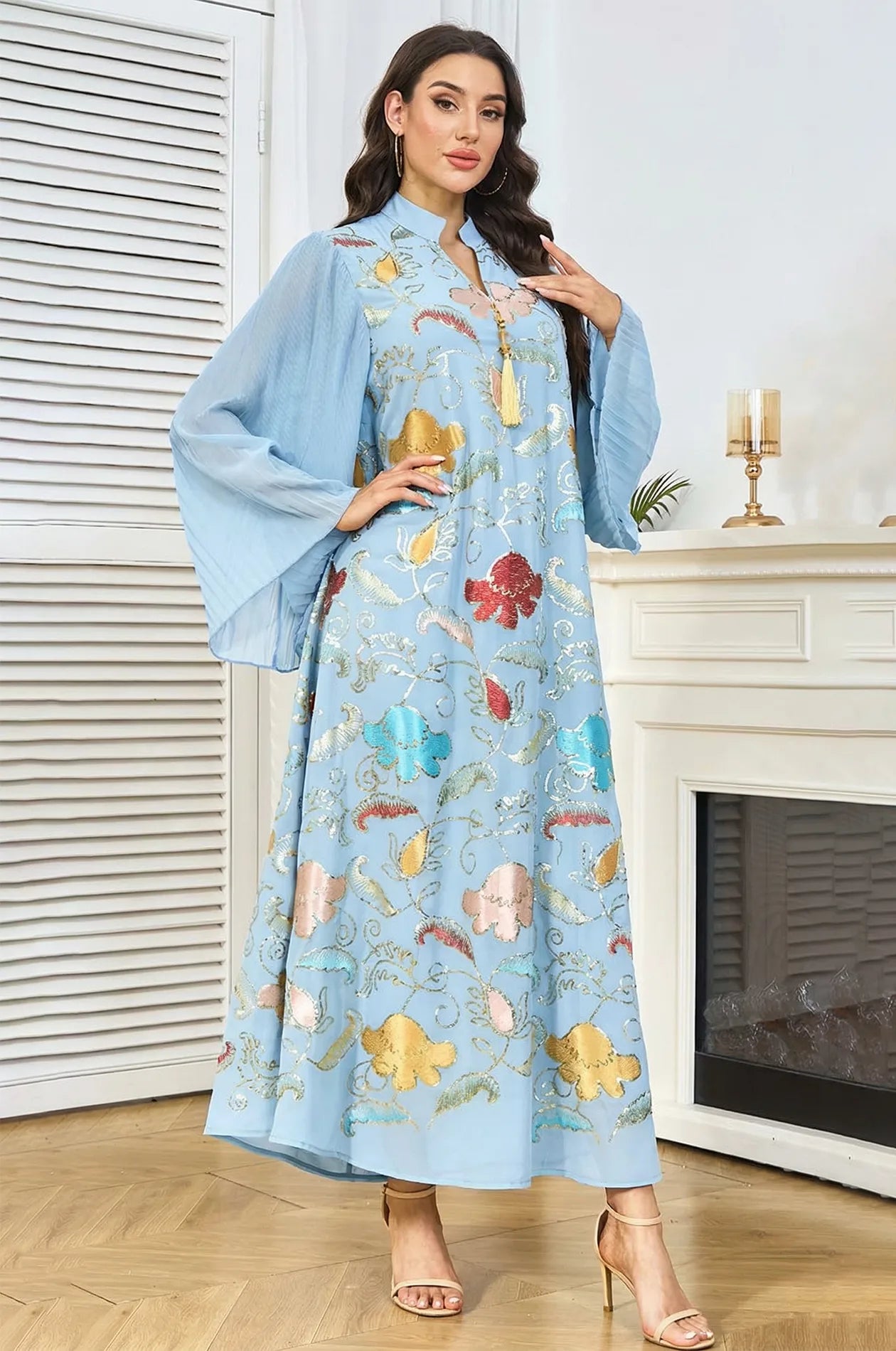 Fashion pose in the Marylin Light Blue Tassel Kaftan, highlighting the dramatic pleated butterfly sleeves and floral motifs.