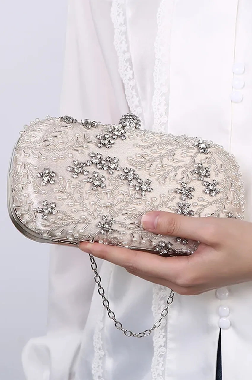 Woman holding a white pearl and crystal beaded clutch with a silver chain, demonstrating size and elegance for wedding styling.