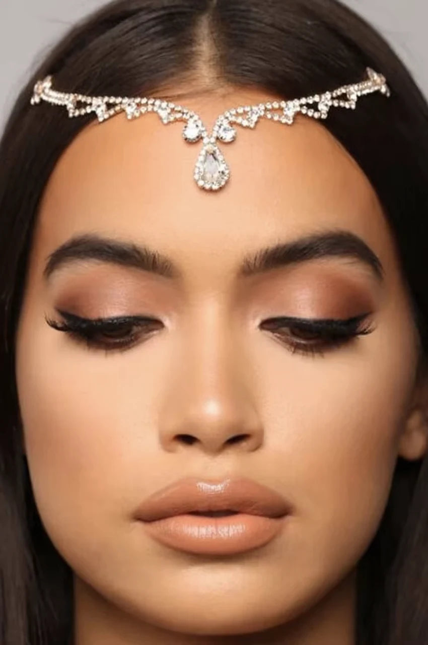 Close-up on a model's forehead wearing the bridal headpiece and teardrop crystal detail.