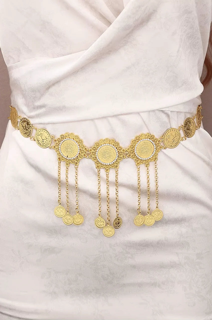 Woman wearing the Naylara gold coin belt over a white dress to show waist fit.